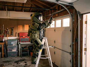 The most dangerous garage door mistake is attempting to... A bomb squad technician in a bomb-proof suit attempts to fix a dangerous garage door torsion spring